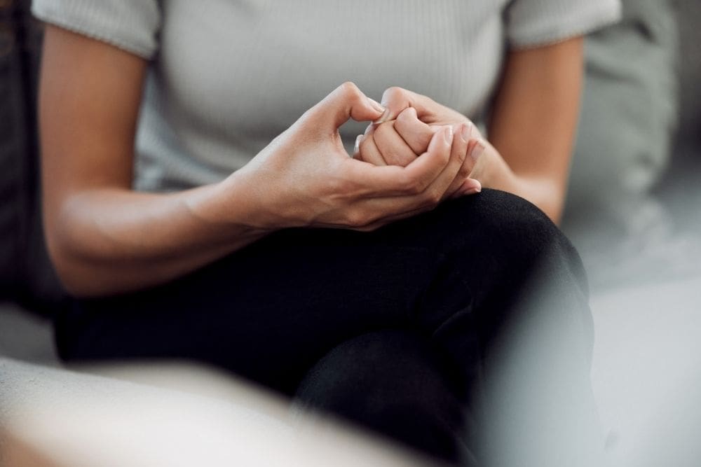 Cropped shot of an unrecognisable woman sitting alone and feeling anxious while picking the skin on her nails