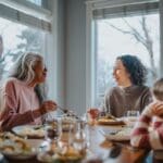 A multigenerational family sits together at a dining table, sharing a meal and conversation in a bright, cozy home setting.