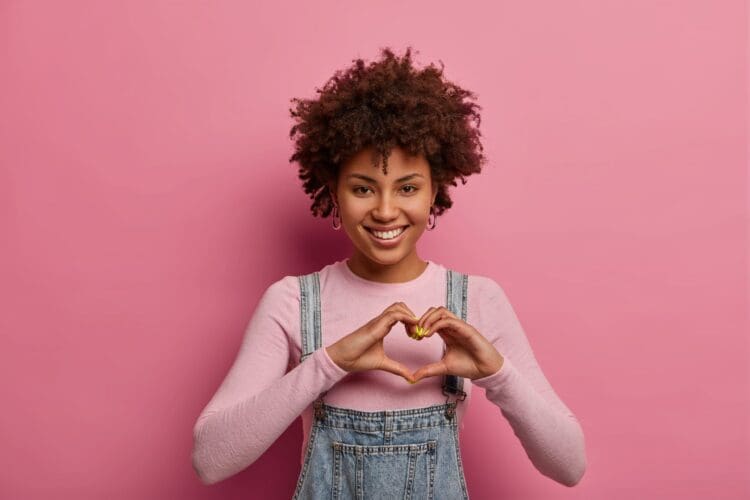 AdobeStock_328749843-e1732040646168 A young woman making a heart with her hands.