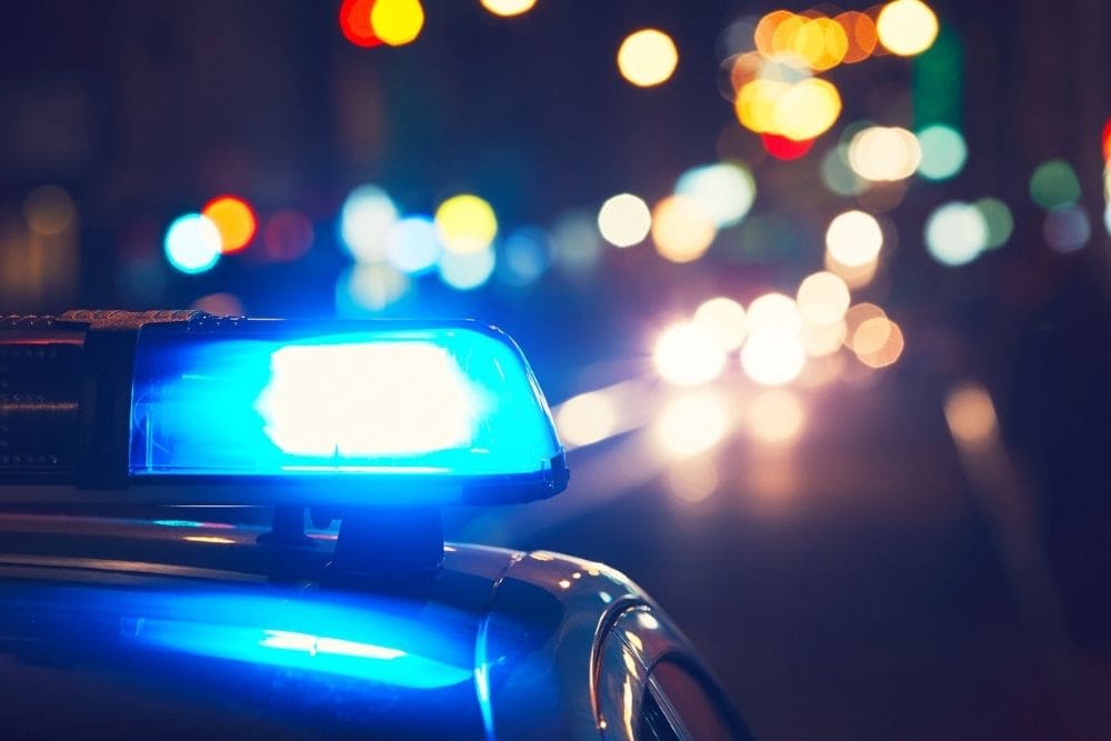 Legal Trouble 1000 x 667 Close-up of a police car's flashing blue lights at night, with blurred city lights in the background.